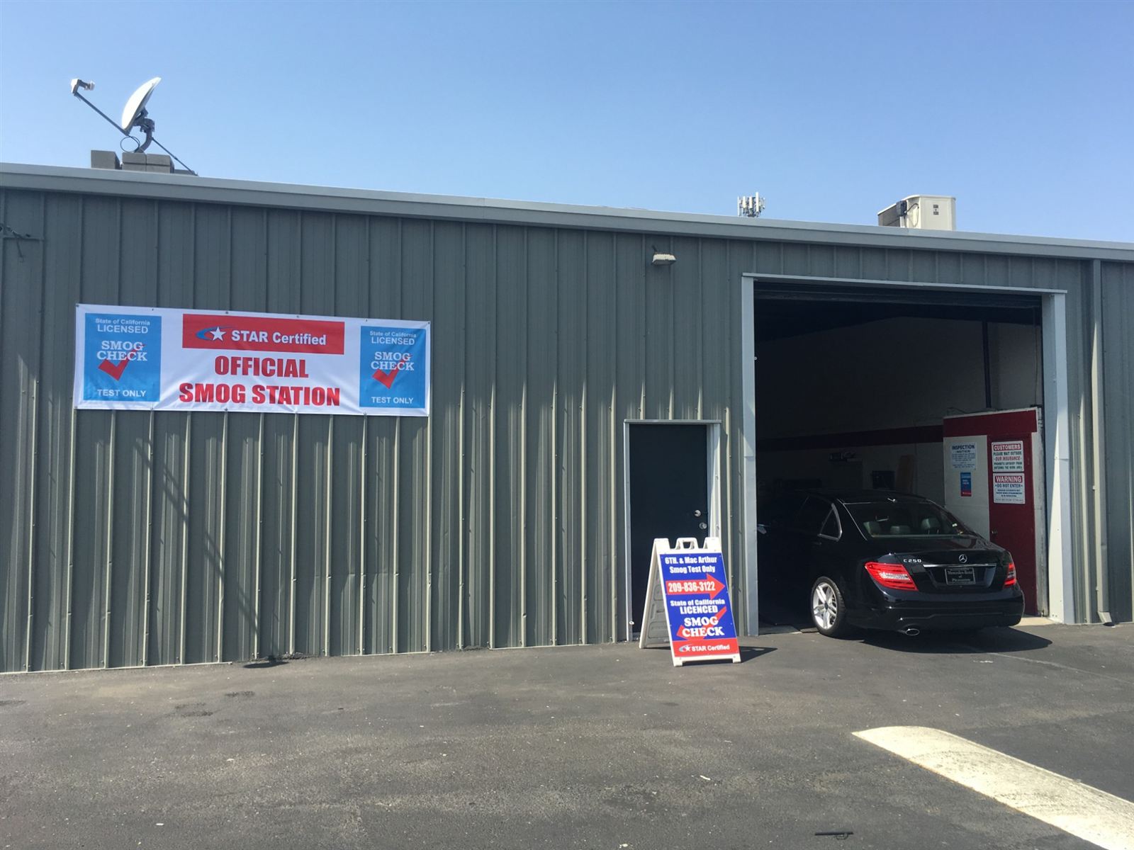 Black Mercedes C250 in the smog test bay beside the STAR Certified Official Smog Station banner in Tracy, CA